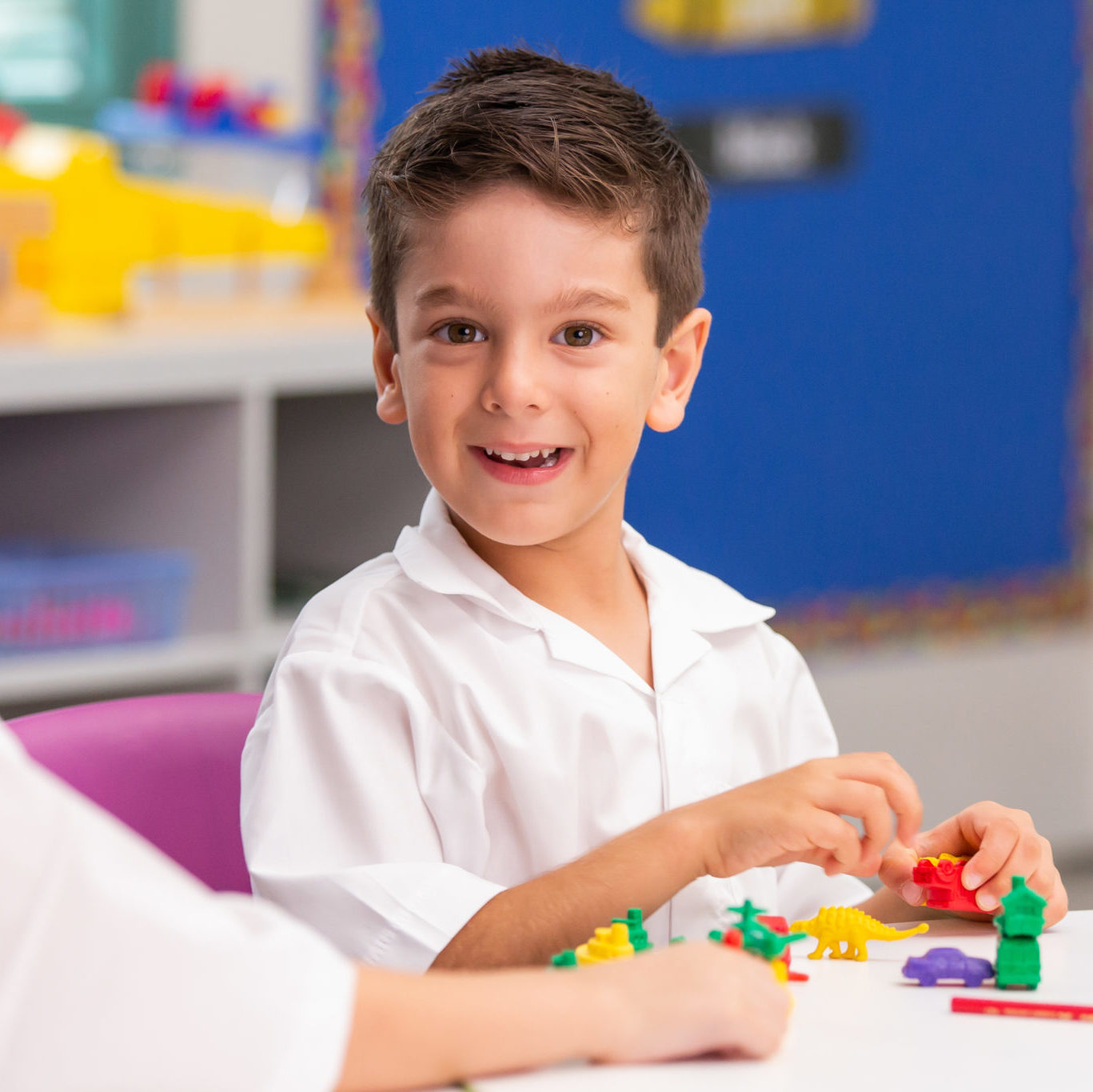 Infants aged boy playing at school desk